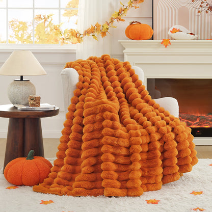 Orange fluffy blanket draped over a chair in a cozy living room with pumpkins and autumn decorations.