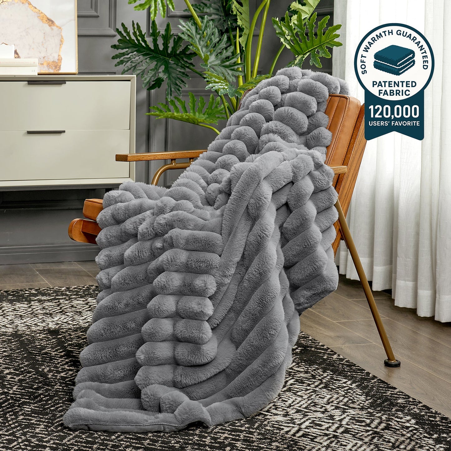 Gray textured blanket draped over a wooden chair in a living room setting with a plant and furniture.