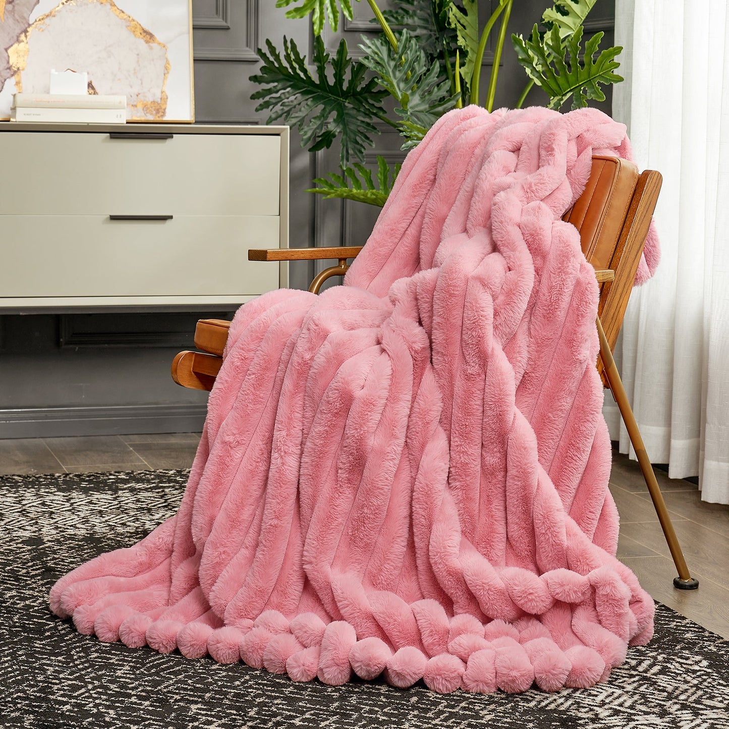 Pink fluffy blanket draped over a chair in a room with decor elements.
