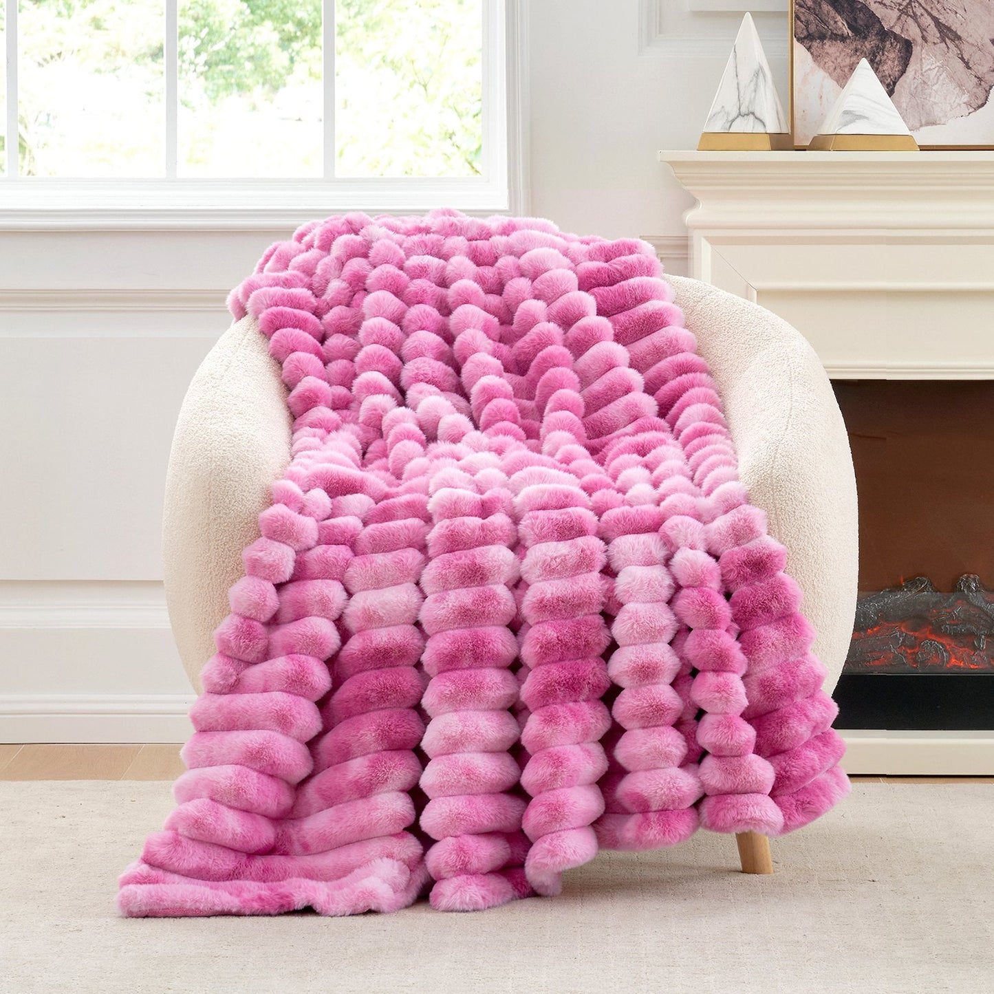 Pink textured blanket draped over a chair in a room with a fireplace.