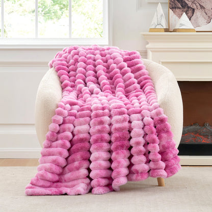 Pink textured blanket draped over a chair in a room with a fireplace.