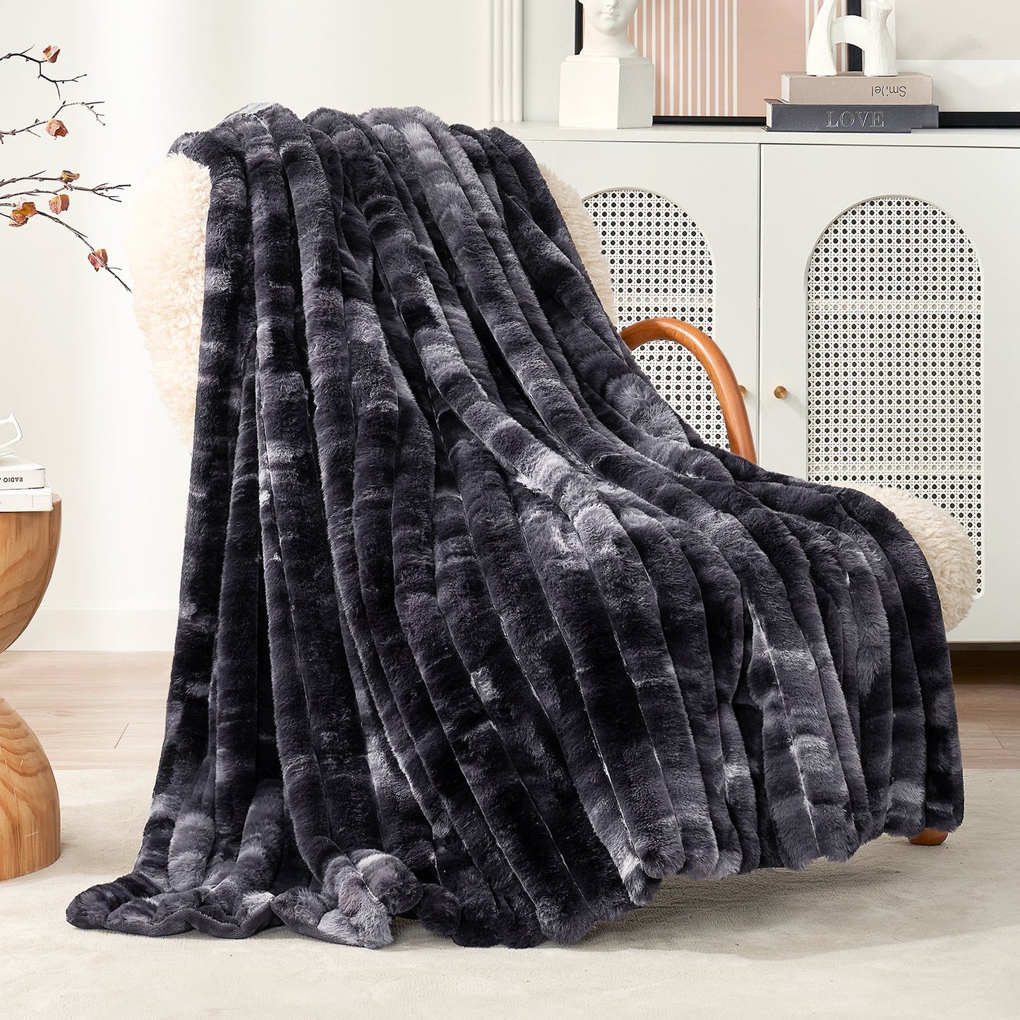Dark gray textured blanket draped over a chair in a room with a white cabinet and decorative items.