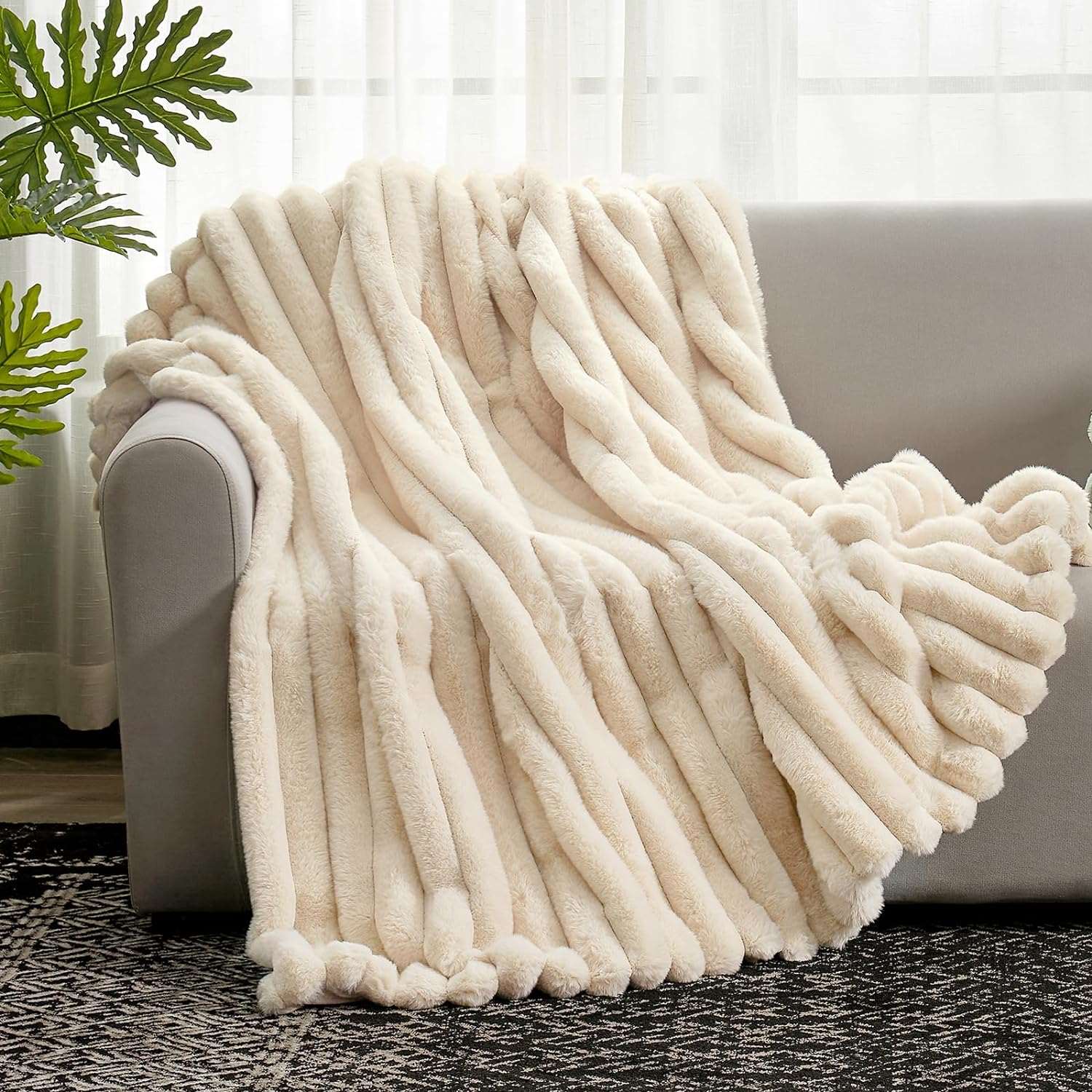Beige blanket draped over a couch with a plant in the background