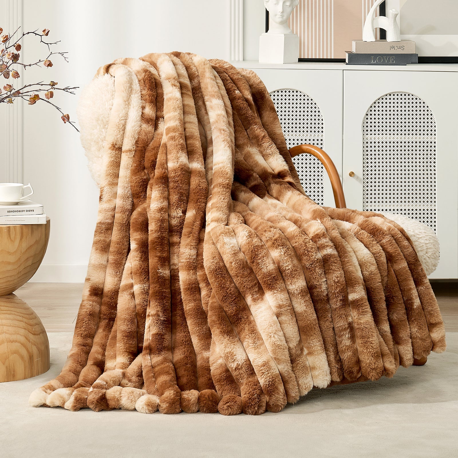 Brown and beige textured blanket draped over a chair in a room with a white cabinet and decorative items.