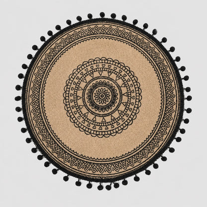 Josh & Tate - SunWeave™ Boho Mandala Placemat - A round beige woven placemat or rug with a black mandala pattern and black pom-pom trim, shown flat against a light gray background.