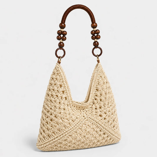 Josh & Tate - SunWeave™ Crochet Hobo Bag - A cream-colored crocheted shoulder bag with a brown leather strap adorned with wooden beads, set against a plain light gray background.