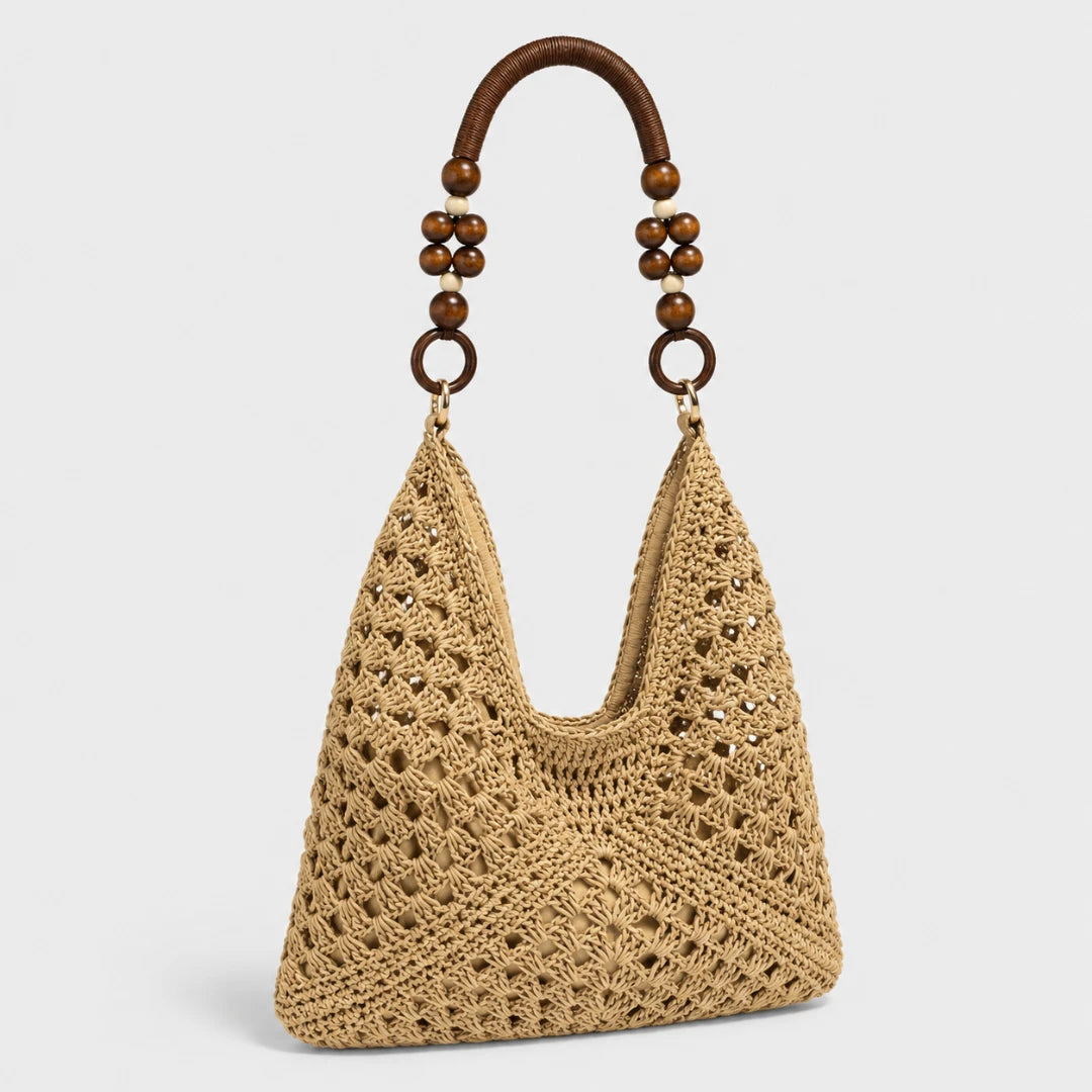 Josh & Tate - SunWeave™ Crochet Hobo Bag - A natural beige crocheted shoulder bag with a curved brown wooden handle decorated with dark brown beads, shown against a light gray background.
