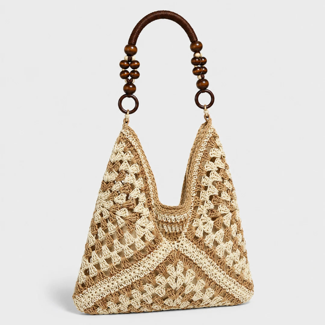 Josh & Tate - SunWeave™ Crochet Hobo Bag - A woven straw shoulder bag with a triangular shape, featuring a textured crochet pattern in natural beige and cream. It has a curved brown wooden handle adorned with dark brown beads and metal rings, set against a light gray background.