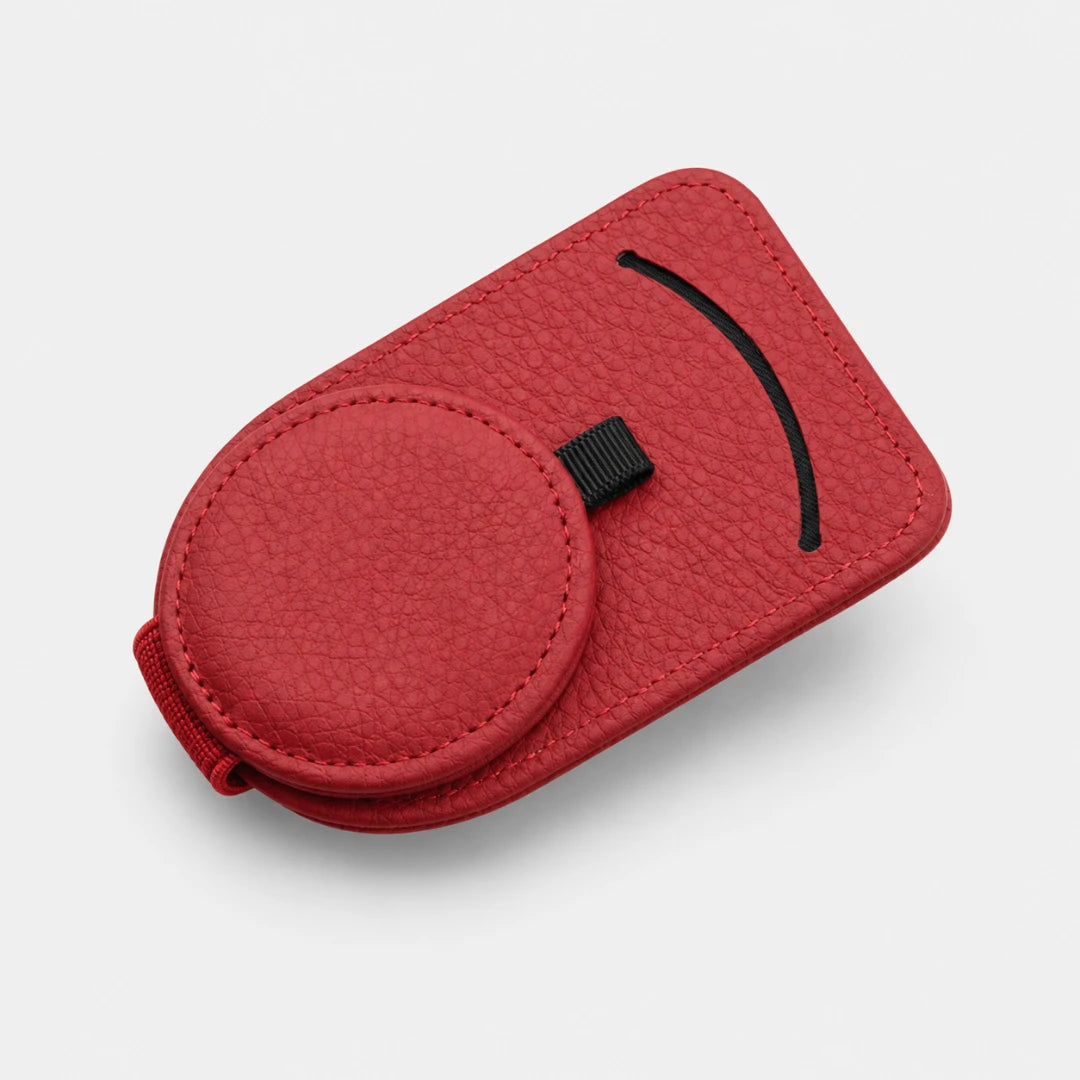 Josh & Tate - SunglassClip™ Car Visor Organizer - A red textured leather phone case with a circular cutout, black curved accent line, and a small black strap, shown on a light gray background.