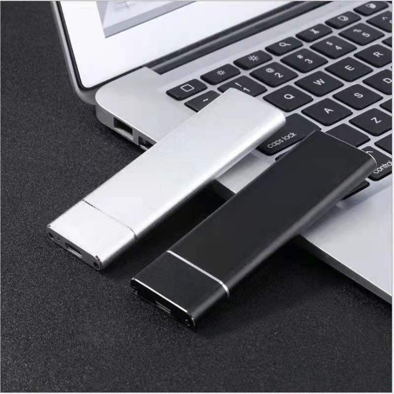 Two USB drives, one silver and one black, in front of a laptop.