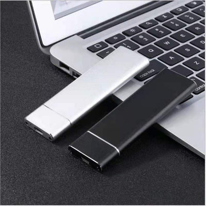 Two USB drives, one silver and one black, in front of a laptop.