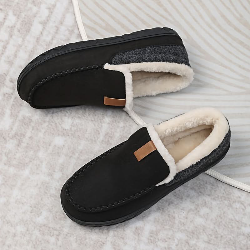 Black slippers with white fur lining on a textured surface