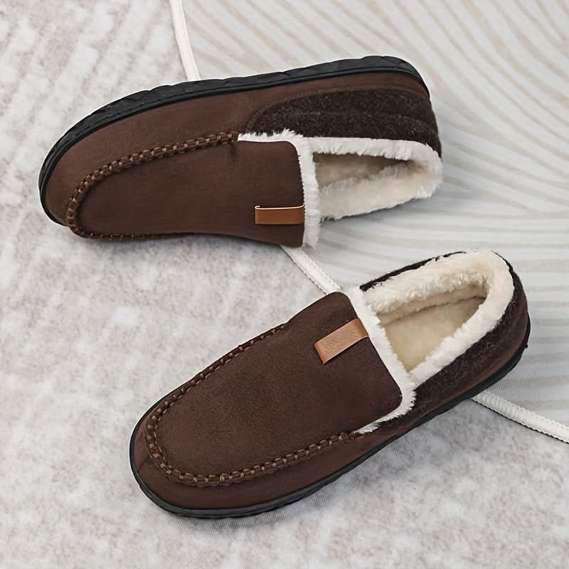 Pair of brown slippers with white fur lining on a textured surface