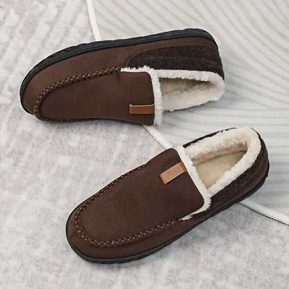 Pair of brown slippers with white fur lining on a textured surface