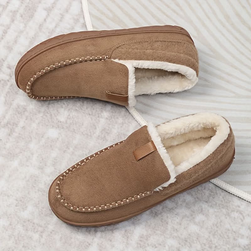 Pair of brown slippers with white lining on a textured surface