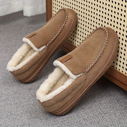 Pair of brown slippers with white fur lining on a textured surface.