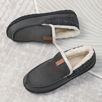 Pair of gray slippers with white fur lining on a textured surface