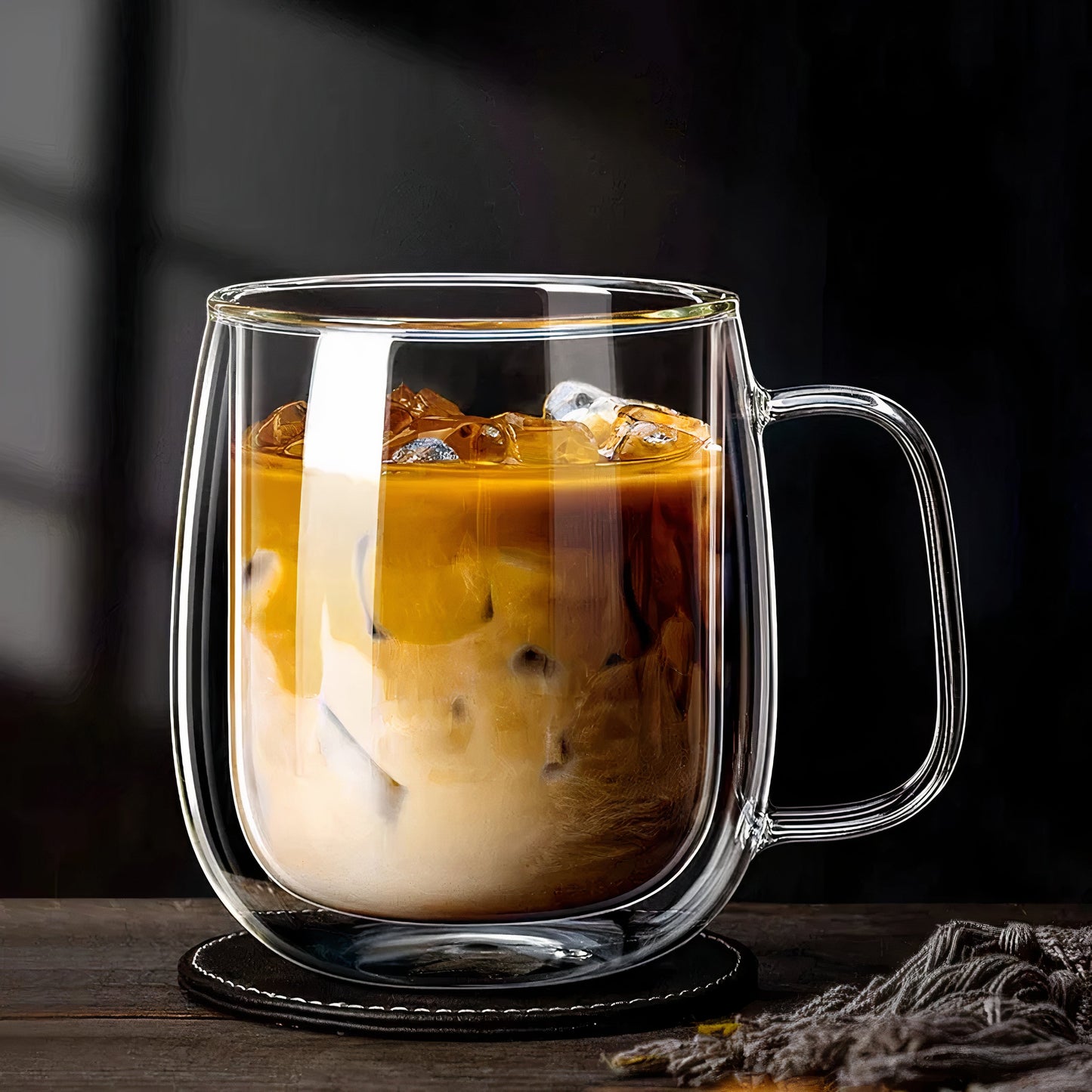 Clear glass mug with iced coffee on a dark background