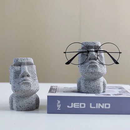 Two stone-like sculptures with faces and glasses on a book titled 'NEW JED LIND'.