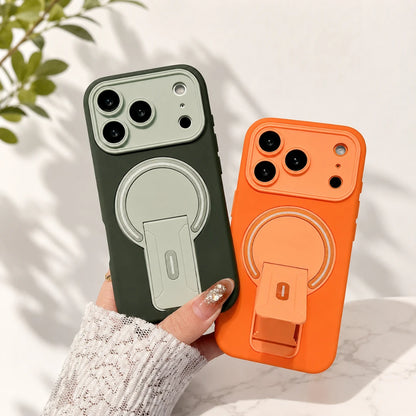Two phone cases with built-in ring stands are held in a hand. One case is dark olive green with a light sage green ring holder, and the other is bright orange with a matching orange ring holder.