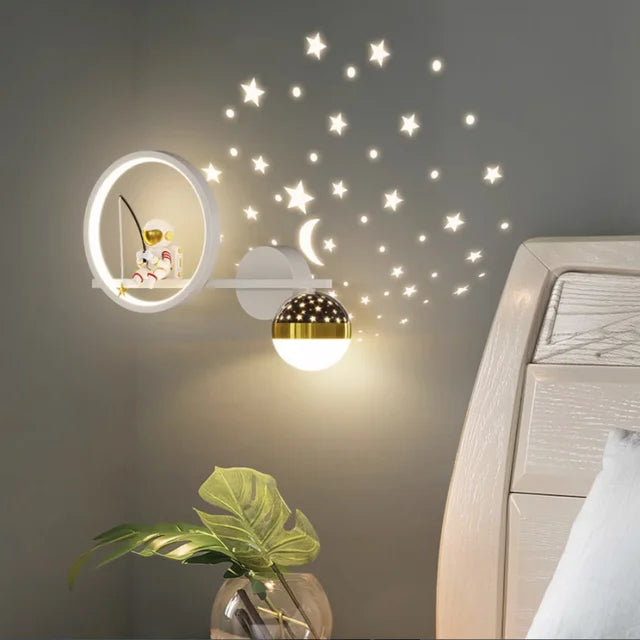 Decorative wall light with star stickers on a wall above a bed.