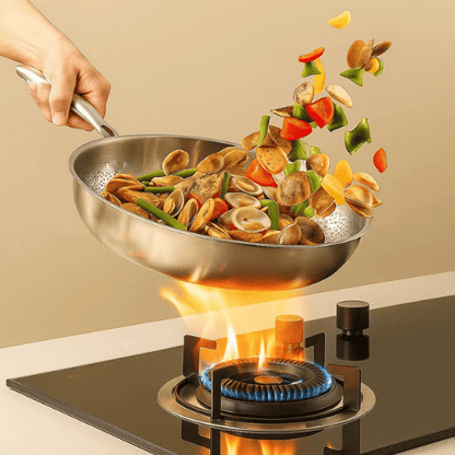 Stir-frying vegetables and clams in a wok over a gas stove with a beige background