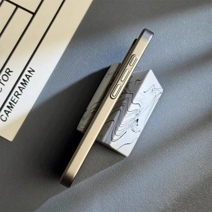 Metallic phone case on a gray surface with a blurred book in the background