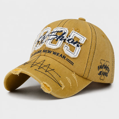 Josh & Tate - TrailFade™ '85 Cap - A distressed mustard yellow baseball cap with embroidered 'Favor It' text on the front, 'FAVORITE JEANS NEW WEAR' on the brim, and 'FAVORITE JEANS' on the side, shown on a light gray background.