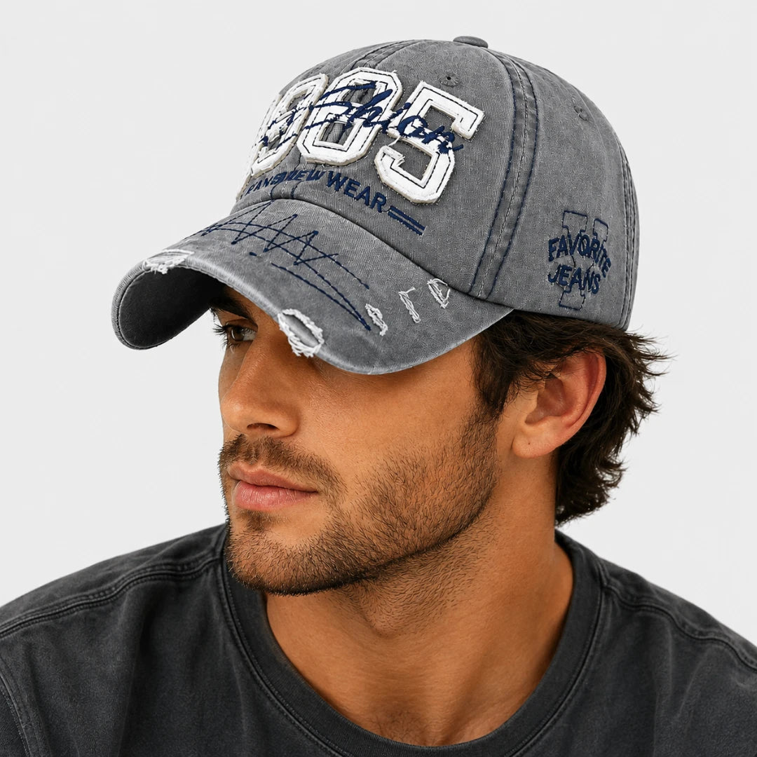 Josh & Tate - TrailFade™ '85 Cap - A man wearing a distressed gray baseball cap with white and navy embroidered lettering that reads 'Favor Jeans' and '365'.