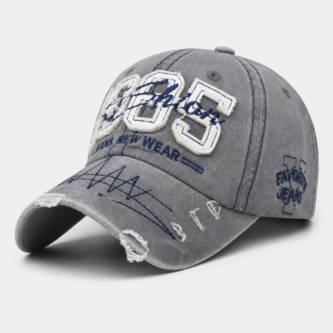 Josh & Tate - TrailFade™ '85 Cap - A gray washed baseball cap with distressed details, featuring white and navy embroidered patches on the front and side.