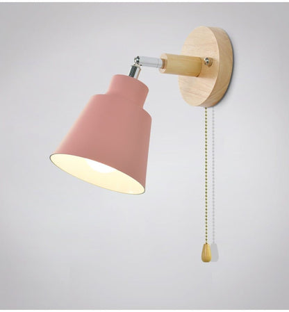 Wall-mounted lamp with pink shade and wooden fixture on a light gray background