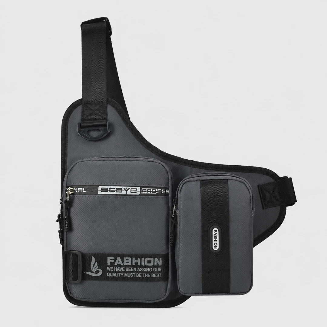 Josh & Tate -UrbanCore™ Crossbody Bag - A dark gray and black sling bag with multiple zippered pockets, featuring 'STAYS PROFESSIONAL' and 'FASHION' text on the front, set against a light gray background.