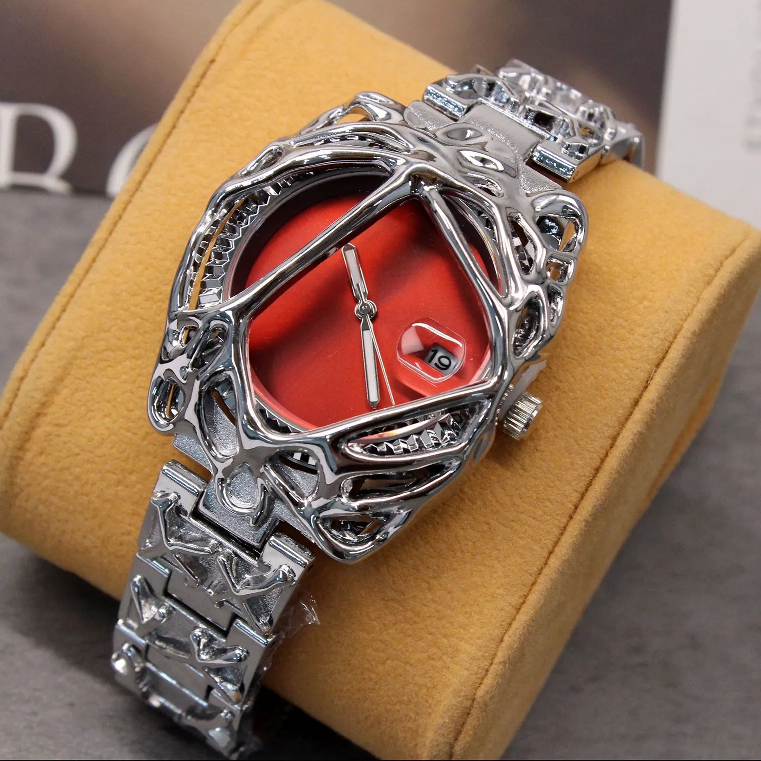 Silver wristwatch with red face on a yellow cushion