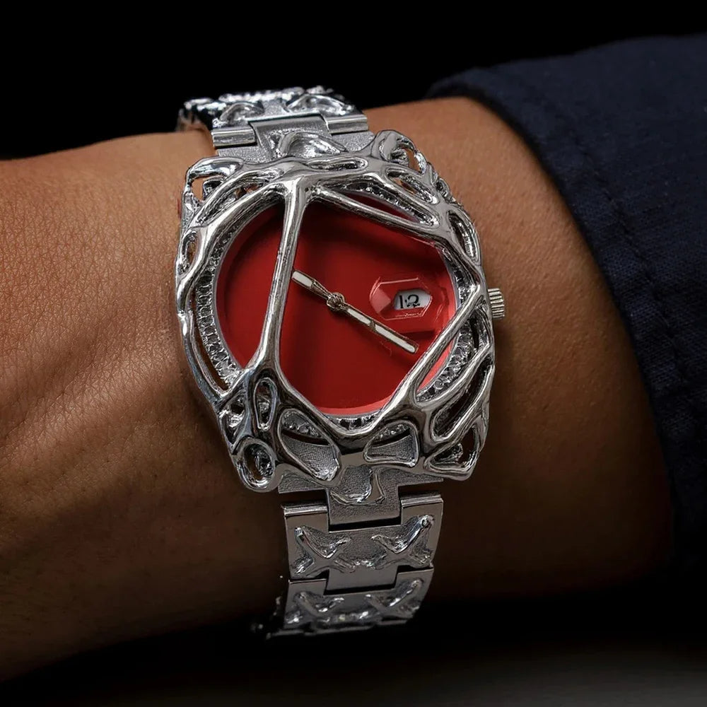 Silver watch with red face on a wrist against a dark background