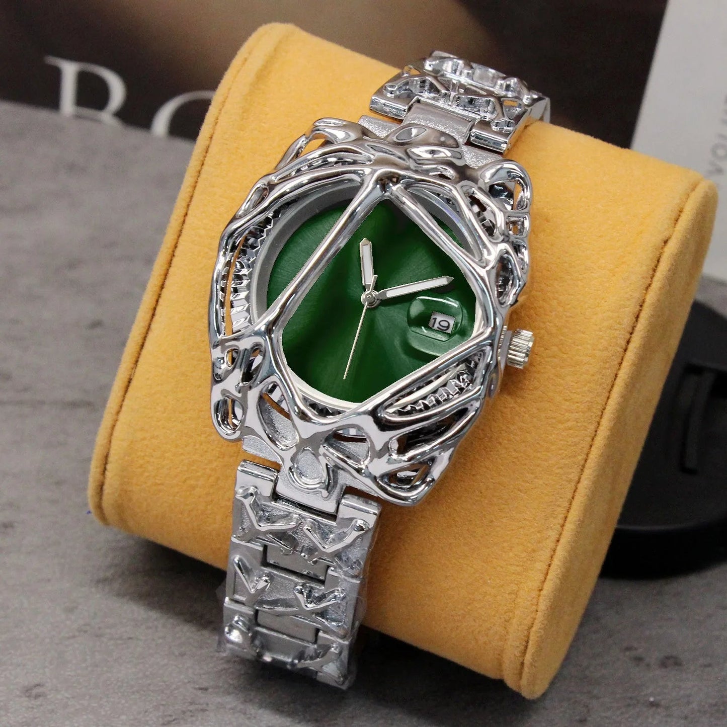 Silver and green watch on a yellow cushion