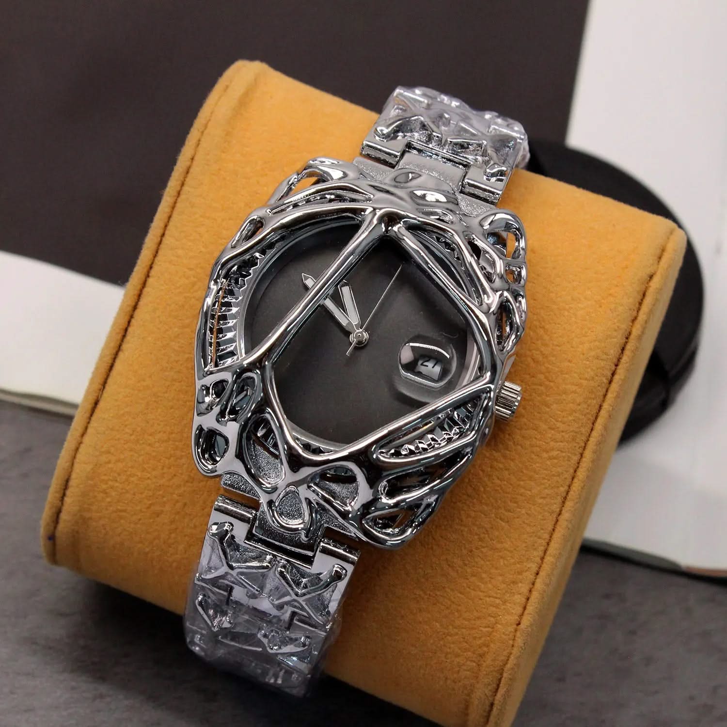 Silver ornate watch on a yellow cushion with a blurred background