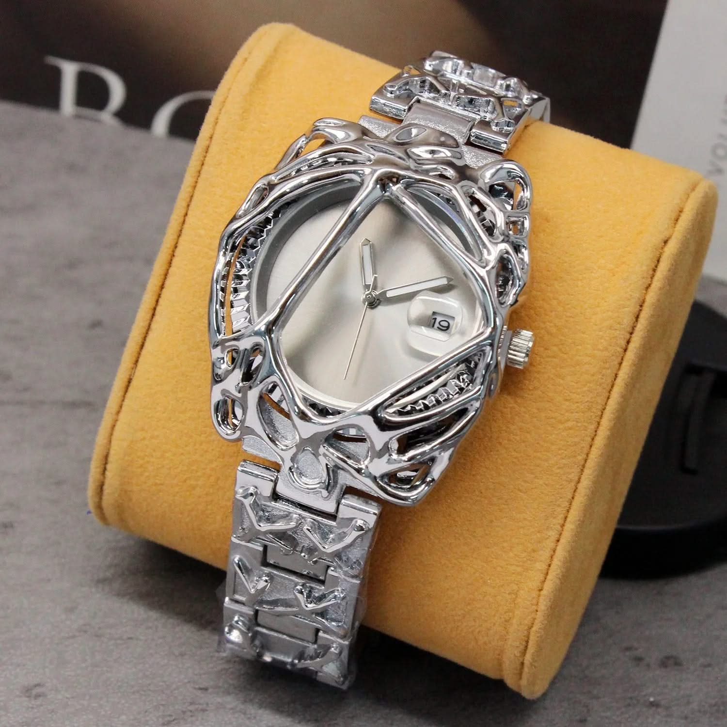 Silver ornate watch on a yellow cushion with a blurred background
