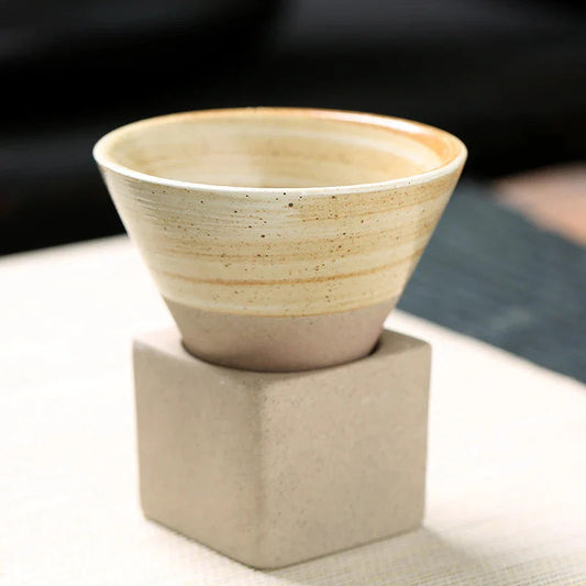 Ceramic cup on a textured block with a blurred background