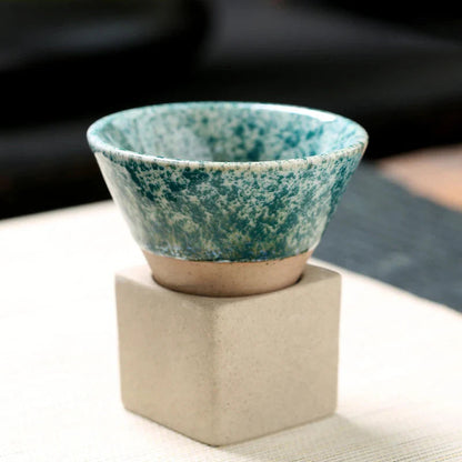 Teal ceramic bowl on a beige stand with a blurred background