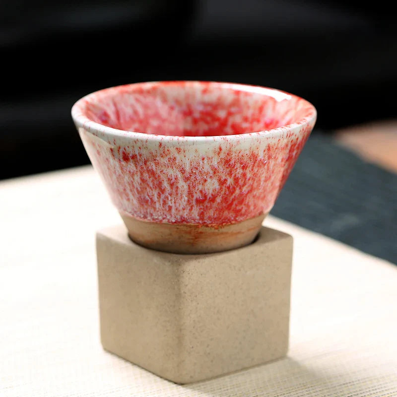 Ceramic bowl with red and white speckled design on a beige stand