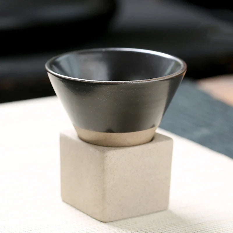 Black ceramic cup on a beige stand with a blurred background