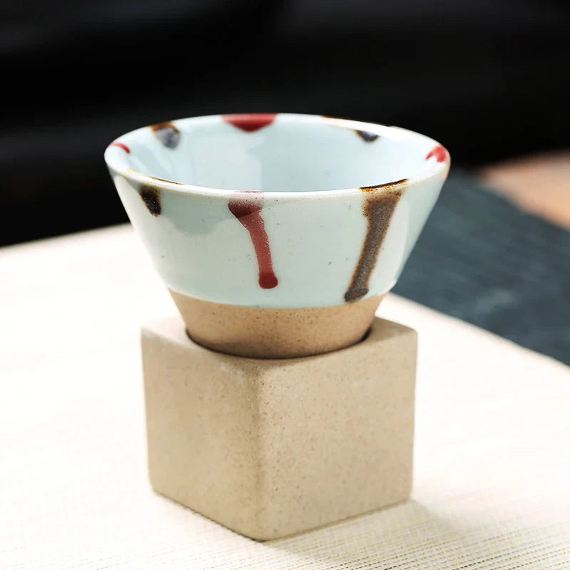 Ceramic cup with abstract design on a beige stand against a blurred background