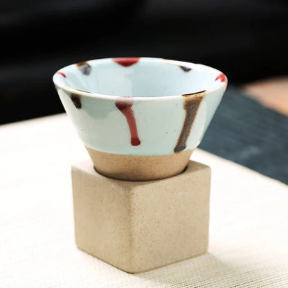 Ceramic cup with abstract design on a beige stand against a blurred background