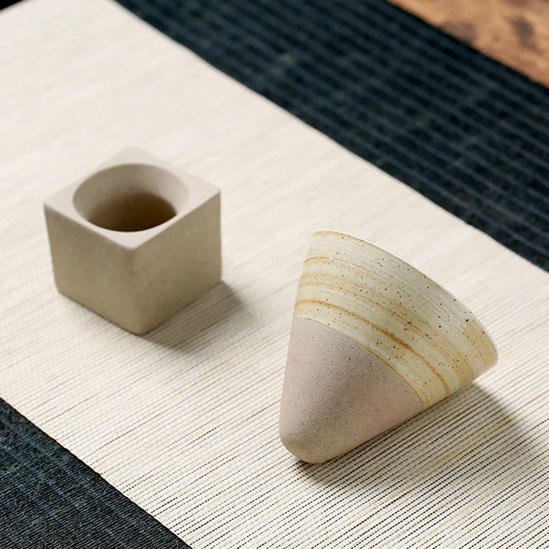 Two ceramic containers on a textured surface with a woven mat background
