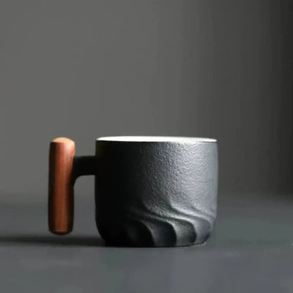 Black ceramic mug with a wooden handle on a gray background