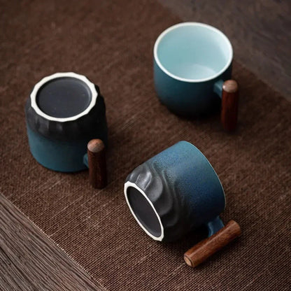 Three blue ceramic mugs with wooden handles on a brown textured surface.