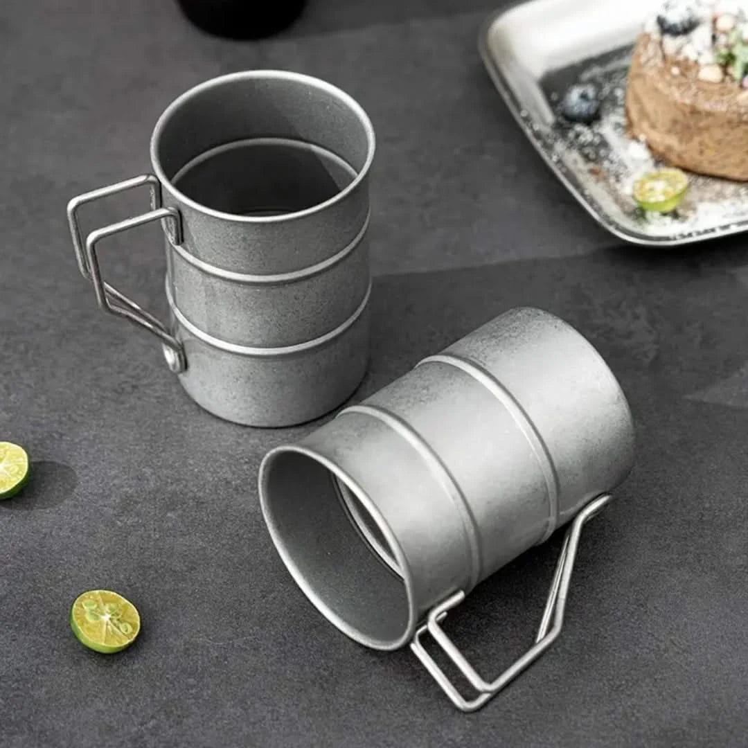 Josh & Tate - Vintage Steel Mug (13oz / 380mL) - Two gray metal mugs with handles on a dark surface with limes and a plate of food.