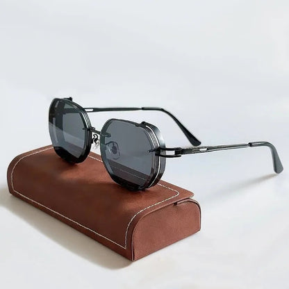 Sunglasses with dark lenses and thin frame on a brown leather case against a light gray background