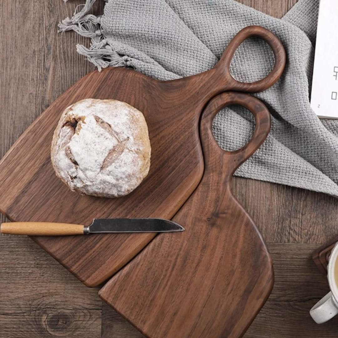 Wooden cutting board with bread and knife on a wooden surface