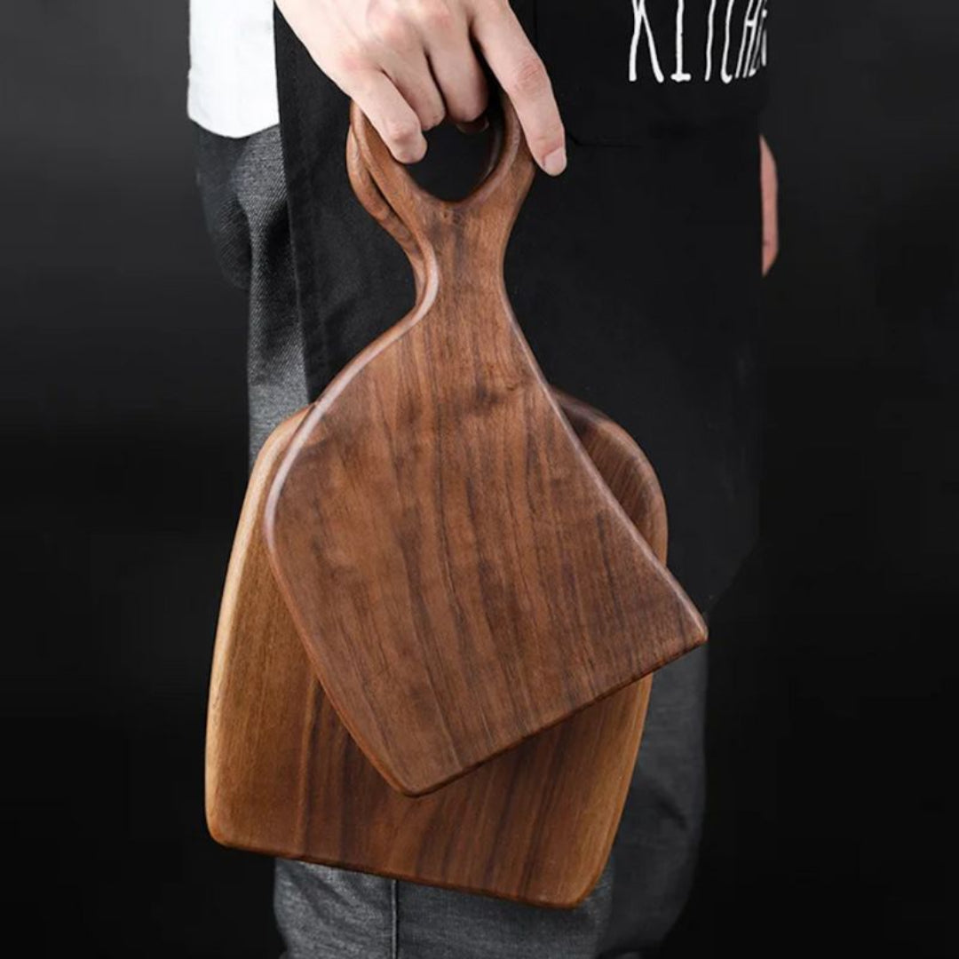 Person holding two wooden cutting boards with a dark background
